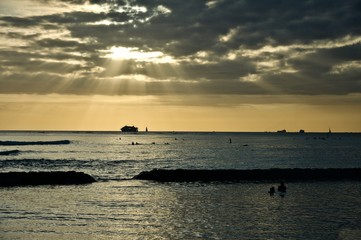 The sun is setting over the horizon at the beach of Waikiki, Hawaii