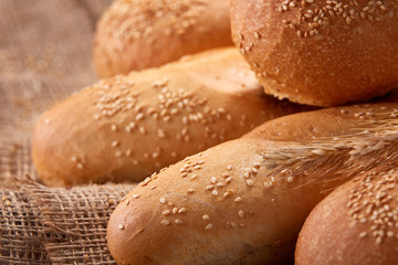 Freshly baked baguette bread and rulls on a burlap napkin on a wooden background. Close up