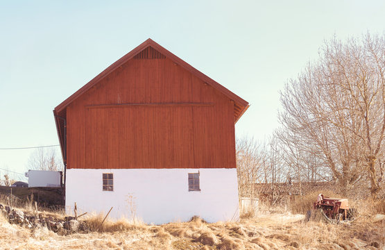 Red farmhouse with two windows during early spring