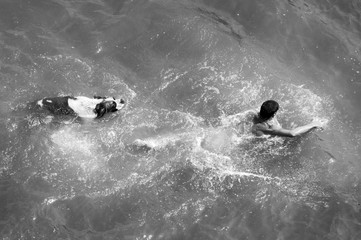 Boy and dog swimming in the sea on sunny summer day