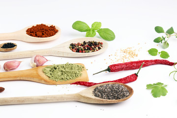 Various herbs and spices in wooden spoons. Flat lay of spices ingredients chilli ,pepper, garlic,dries thyme, nutmeg,rosemary, sweet basil and matcha on white background