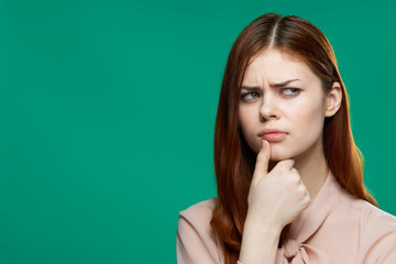 puzzled woman with finger near mouth, green background