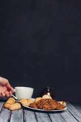Cup in hand and dessert on a wooden background