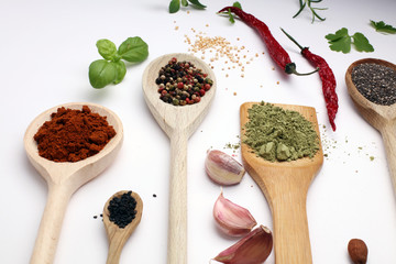 Various herbs and spices in wooden spoons. Flat lay of spices ingredients chilli ,pepper, garlic,dries thyme, nutmeg,rosemary, sweet basil and matcha on white background