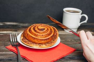 a cinnamon roll and a knife with a fork in his hand