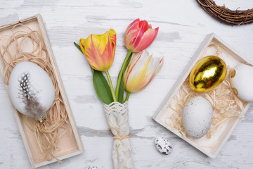 Easter eggs and tulips over wooden background.