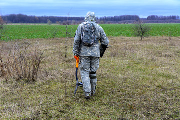Man with a device for finding treasures with a shovel on the field