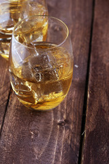 glass of whiskey with ice on a wooden