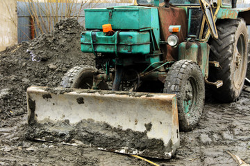 Fototapeta premium An old Soviet tractor digs and loads waste stone processing near the shop