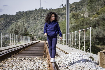 Niña jugando feliz en las vías del tren.