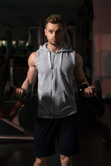 Bodybuilder Exercising Biceps With Dumbbells In Gym