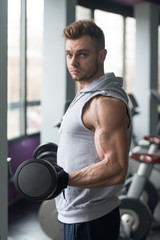 Fototapeta na wymiar Bodybuilder Exercising Biceps With Dumbbells In Gym