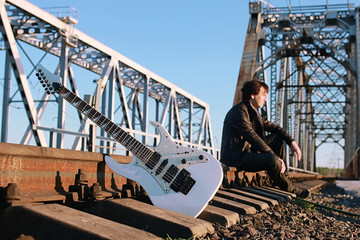 Man with an electric guitar in the industrial landscape outdoors