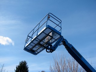Boom lift reaching high up. Blue elevated work bucket platform, articulating bending arm. © Irra