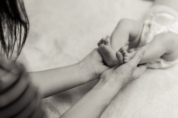 Mother holding tiny foot of newborn baby