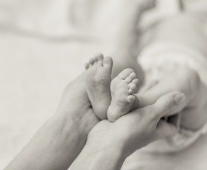 Mother holding tiny foot of newborn baby