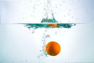 Fototapeta na wymiar Orange in a stream of water on a white background, studio light