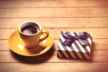 photo of cup of coffee and cute wrapped gift on the wonderful brown wooden background