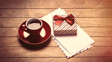 photo of cup of coffee, envelopes and cute wrapped gift on the wonderful brown wooden background