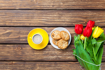 bunch of tulips, plate full of cookies and cup of coffee on the wonderful brown wooden background
