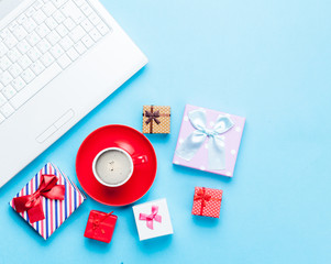 cute gifts, laptop and cup of coffee on the wonderful blue background