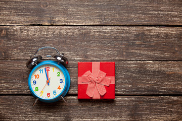 photo of cute wrapped gift and alarm clock on the wonderful brown wooden background