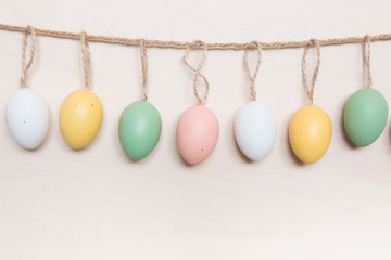 Easter eggs hanging on rope over wooden background.