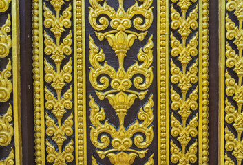 Fototapeta na wymiar Temple door decorated with gold leaf designs Thailand