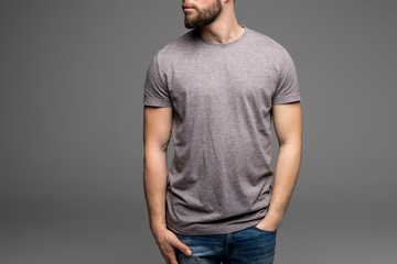 Fototapeta premium A man in a grey t-shirt and denims holds his hands in pockets.