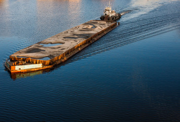 Tugboat pushing barge with sand - obrazy, fototapety, plakaty