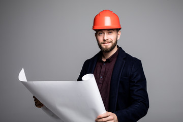 Portrait of an architect builder studying layout plan of the rooms, serious civil engineer working with documents on construction site on grey background