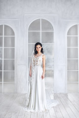 Obraz premium Beauty portrait of bride wearing fashion wedding dress with feathers with luxury delight make-up and hairstyle, studio indoor photo. 