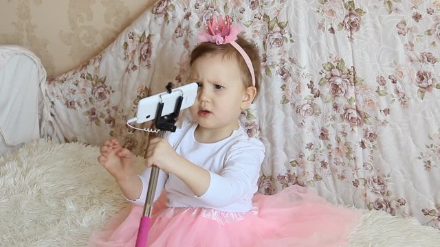 A little beautiful funny girl takes pictures of Selfie on the phone