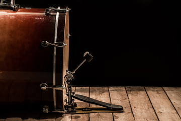 Fototapeta na wymiar percussion instrument, bass drum with pedal on wooden boards with a black background