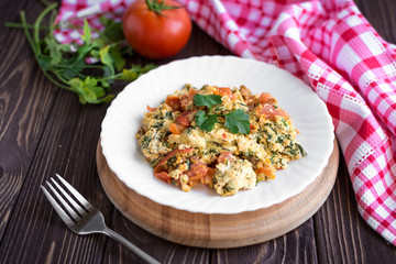 Fried eggs with tomato on dark wooden table