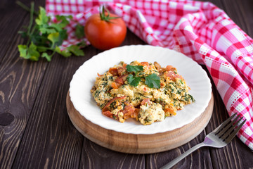 Fried eggs with tomato on dark wooden table