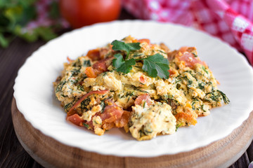 Fried eggs with tomato on dark wooden table