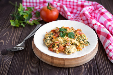 Fried eggs with tomato on dark wooden table
