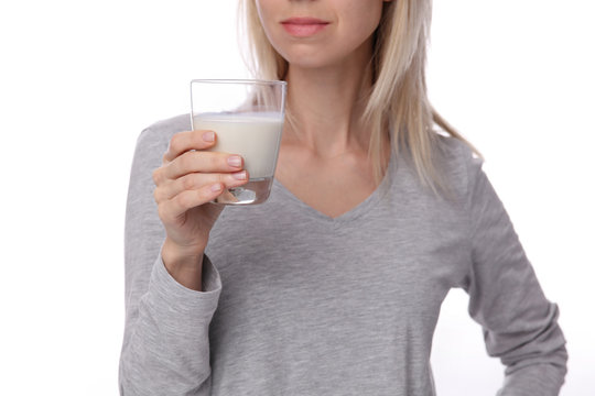Woman holding a glass of milk close up isolated on white background. Dairy products