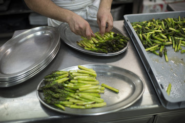 Cook's hands placing green asparagus