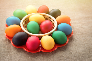 Multicolored easter eggs in a plate for eggs on a cloth background. The concept of a holiday and a happy Easter.