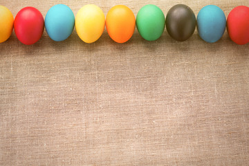 Obraz premium Multicolored easter eggs in a row on a cloth background. The concept of a holiday and a happy Easter. With space for text