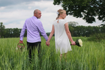 Couple lovers walking in field in summer day