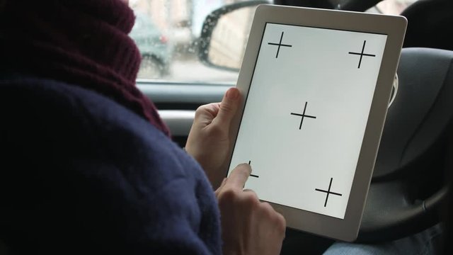 View from over shoulder of womans hands using tablet pc with screen template sitting behind the wheel of car. Crop close-up shot.