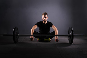 Handsome weightlifter preparing for training. Shallow depth of field, selective focus. Low key