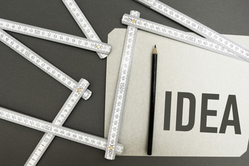 Folding ruler, a blank sheet of paper and a pencil on a gray background. Idea.