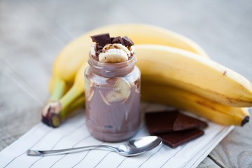 Fototapeta na wymiar Chocolate pudding with banana in a glass jar on a textile background