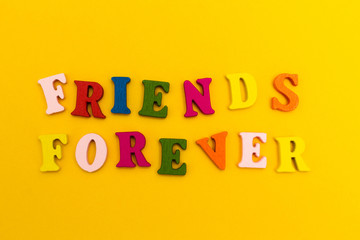Multicolored letters on a yellow background. Friends forever.