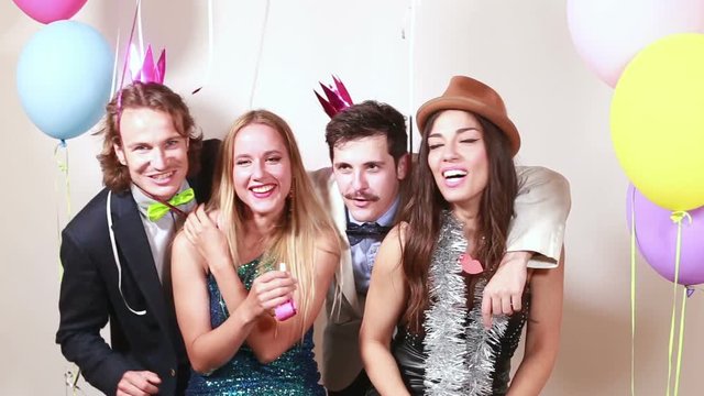 Four young crazy friends having great time in party photo booth