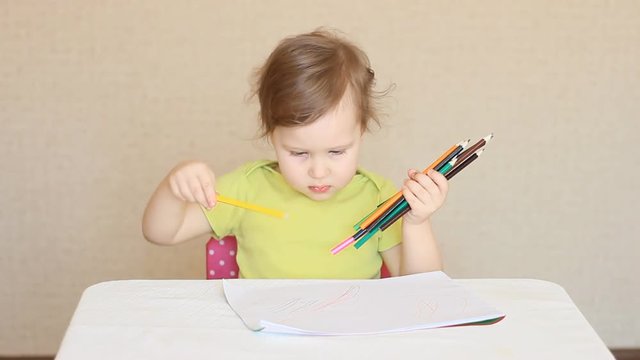 A little girl draws with colored pencils